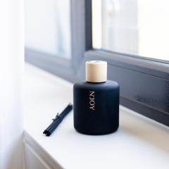 Diffuseur d’ambiance chèvrefeuille noir minimaliste sur rebord de fenêtre / Minimalist black honeysuckle diffuser on windowsill / Minimalistische zwarte kamperfoelie diffuser op vensterbank
