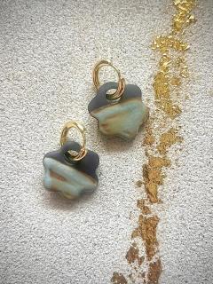 Boucles d’oreilles artisanales en porcelaine noire – petite fleur sur créole dorée, bijou fait main. / Handgemaakte oorbellen in zwarte porselein – kleine bloem met gouden ring, lokaal juweel. / Handmade black porcelain earrings – small flower on gold hoop, elegant artisan jewelry.