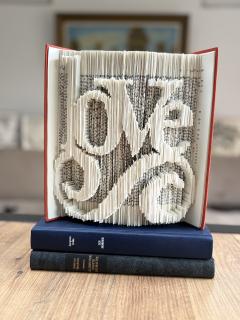 Livre sculpté à la main avec le mot “LOVE” en lettres capitales – création artisanale unique faite à partir de papier recyclé. Parfait comme décoration de mariage, cadeau de Saint-Valentin ou attention personnalisée. / Handgevouwen boek met “LOVE” – uniek ambachtelijk cadeau voor huwelijk of Valentijn / Handmade folded book “LOVE” – recycled paper, romantic wedding or Valentine’s gift