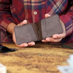 Portefeuille homme en cuir tenu en main, couture artisanale et pince à billets, cadeau élégant et durable, made in Belgium / Leren herenportefeuille in de hand, ambachtelijke stiksels en biljetklem, elegant en duurzaam cadeau, made in Belgium / Men’s leather wallet held in hand, handcrafted stitching and money clip, elegant and durable gift, made in Belgium