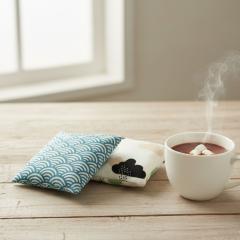 Bouillotte en lin naturel sur canapé, coussin chauffant réutilisable écoresponsable, moment cocooning durable / Herbruikbaar linnen warmtekussen voor cocoonmoment, duurzaam en milieuvriendelijk / Reusable linen heating cushion for cozy home moments, eco-conscious sustainable comfort accessory