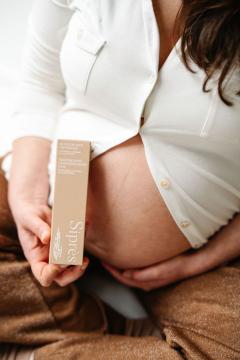 Huile de soin appliquée sur ventre de femme enceinte, rituel bien-être pour la maternité / Verzorgende olie aangebracht op zwangere buik, welzijnsritueel tijdens de zwangerschap / Care oil applied on pregnant belly, wellness ritual for maternity