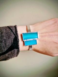Bracelet en vitrail bleu turquoise porté au poignet, verre artisanal soudé main monture argentée, bijou créateur belge moderne et lumineux, cadeau femme made in Belgium / turquoise stained glass bracelet worn on wrist handcrafted Belgian designer jewelry / turquoise glas-in-lood armband gedragen aan de pols Belgisch handgemaakt juweel