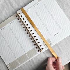Ruban marque-page doré glissé dans un agenda à spirale – Les agendas de Juliette / Gouden leeslint in een agenda met spiraal – Les agendas de Juliette / Gold ribbon bookmark tucked into a spiral planner – Les agendas de Juliette
